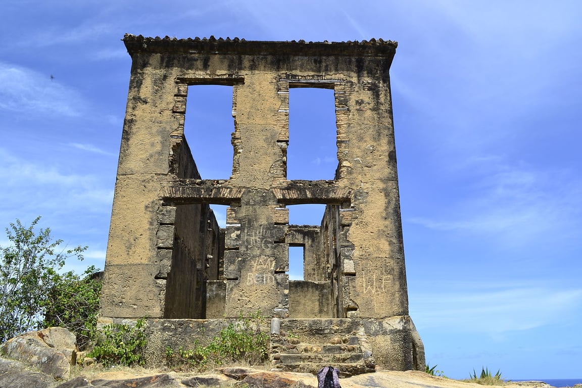 Paisagem rural da Zona da Mata Sul de Pernambuco ao entardecer, com vegetação e ruínas de construção histórica ao fundo