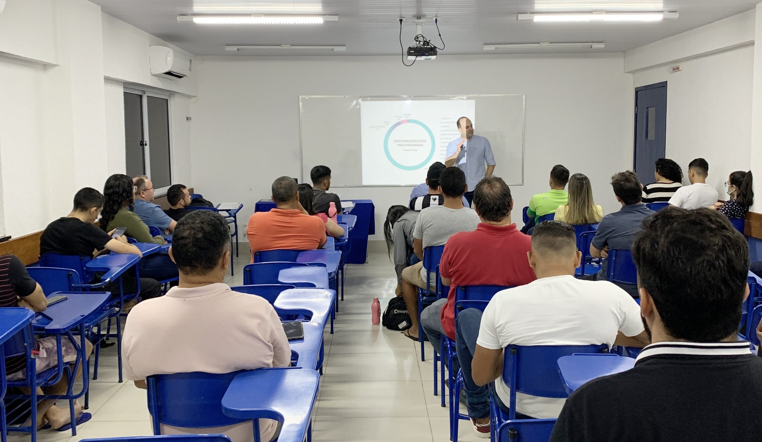 Sala de aula de Engenharia Civil, professor no quadro e estudantes atentos