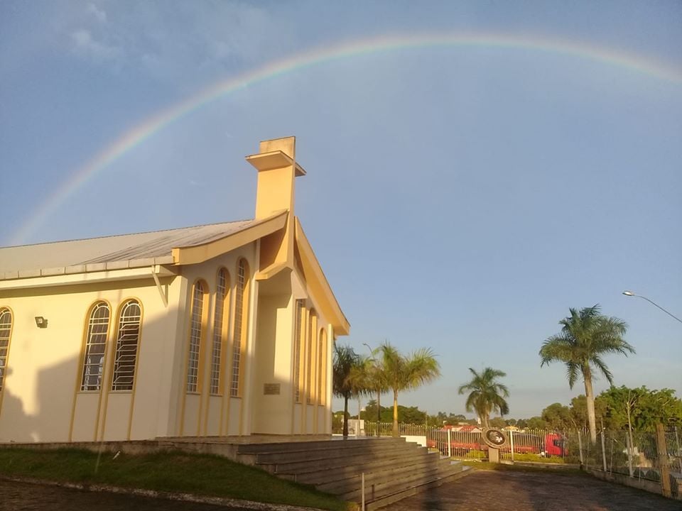 Vista urbana de Pedro Canário, com igreja e arco-íris ao fundo