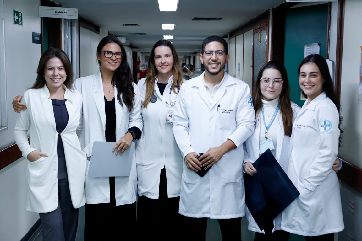 Profissionais de saúde em corredor de hospital público, com jalecos.