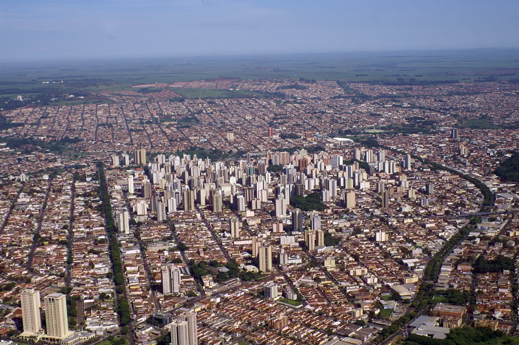 Vista aérea de Ribeirão Preto SP ao entardecer, com a malha urbana e prédios destacados no horizonte