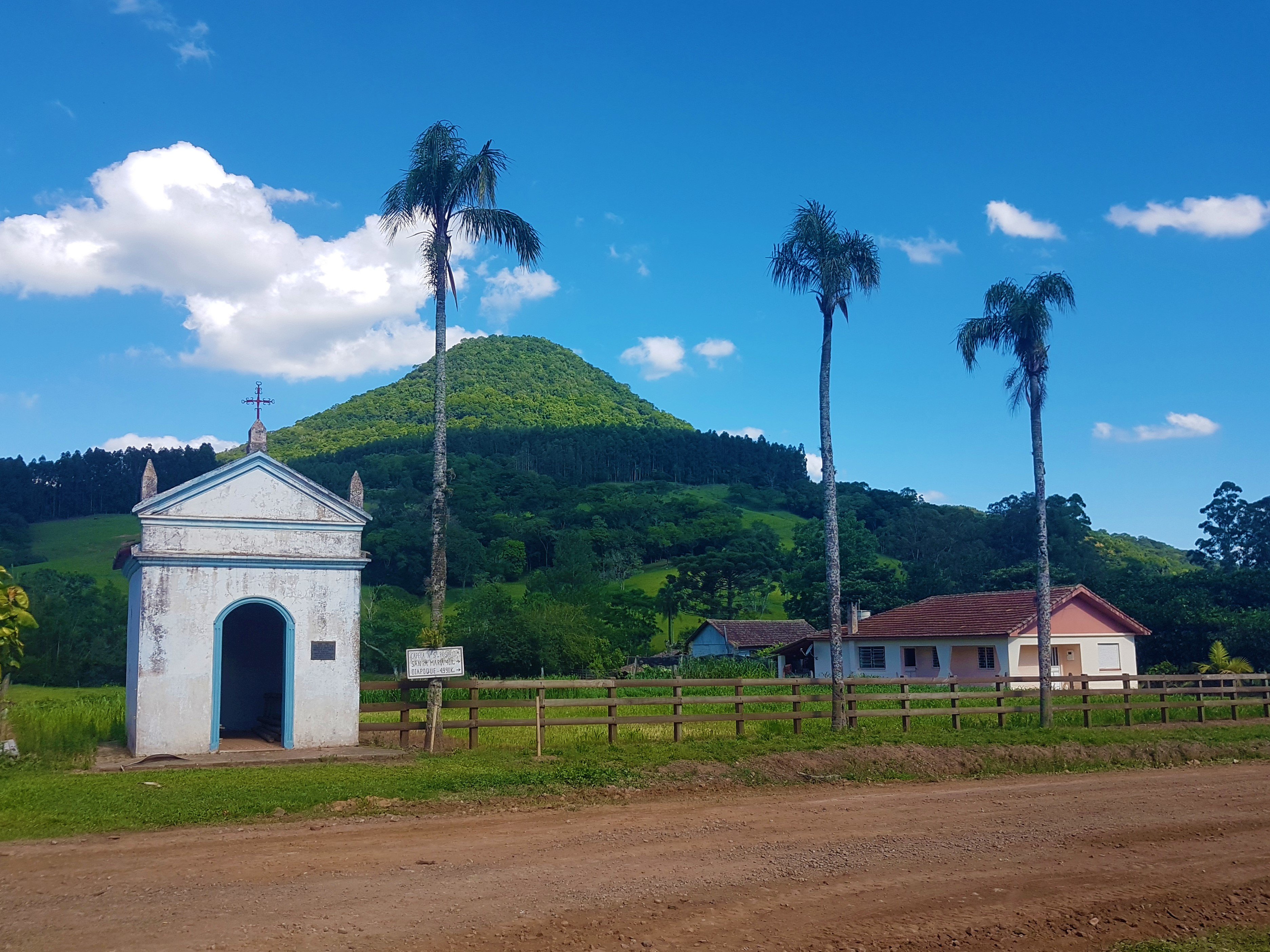 Vista de pequena cidade do interior com capela e morros ao fundo