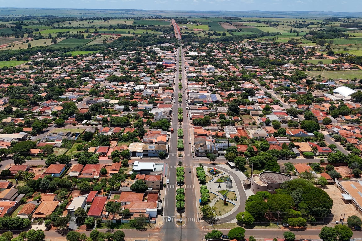 Vista aérea de uma pequena cidade com ruas arborizadas e espaçamentos rurais ao fundo.