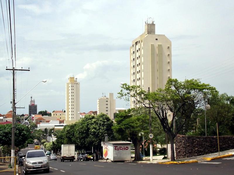Avenida principal de Dracena SP com comércio e vegetação em dia claro