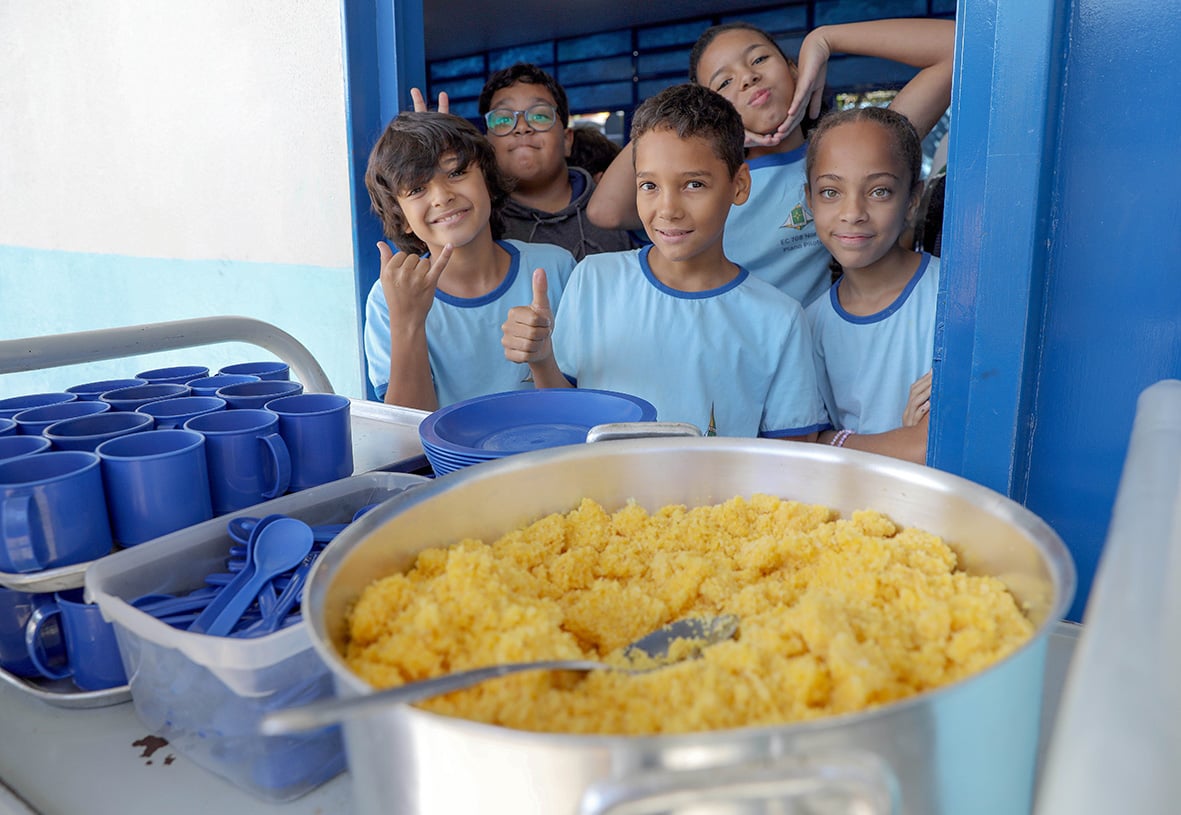 Refeitório escolar com merendeira e alunos