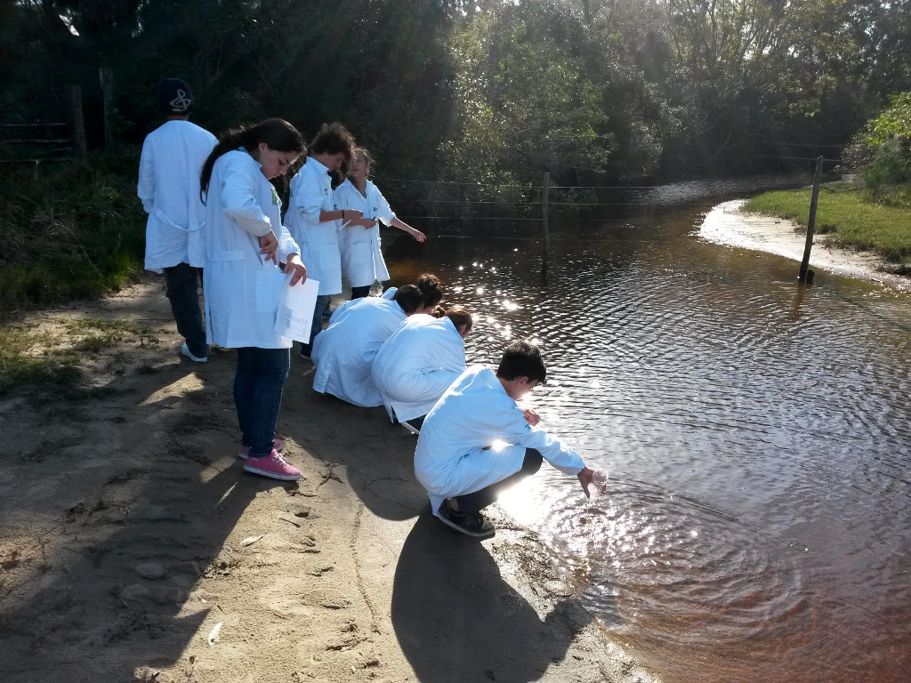 Técnicos ambientais em coleta de água em lagoa costeira