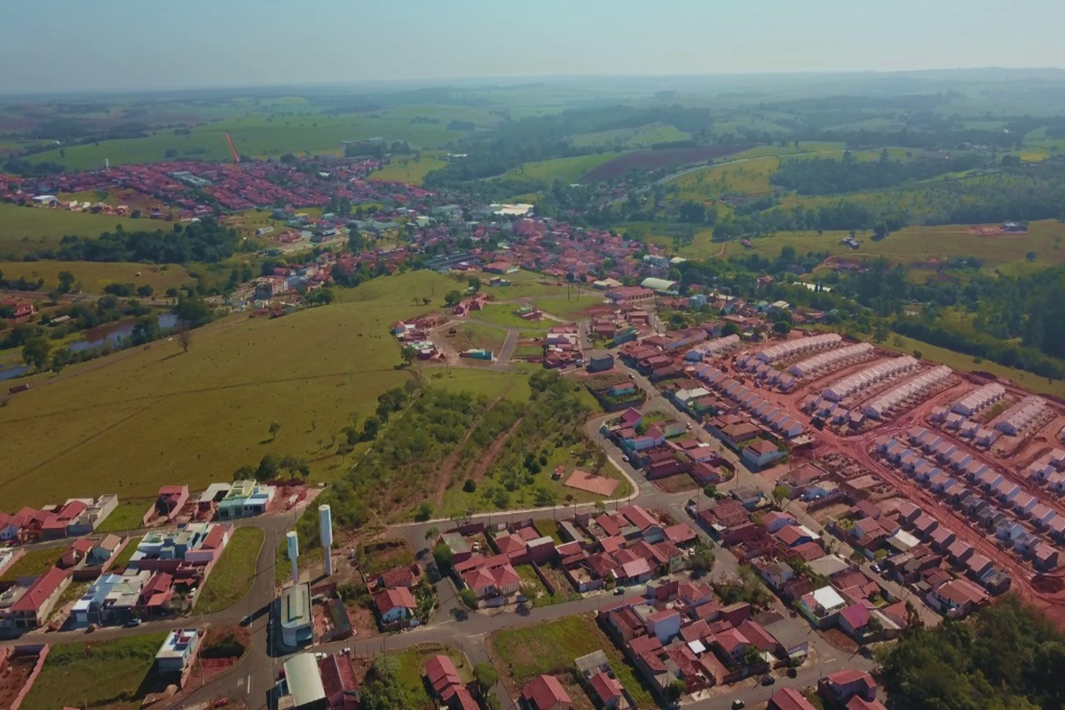 Vista aérea da cidade com áreas residenciais e vegetação em Pardinho SP, em dia ensolarado.