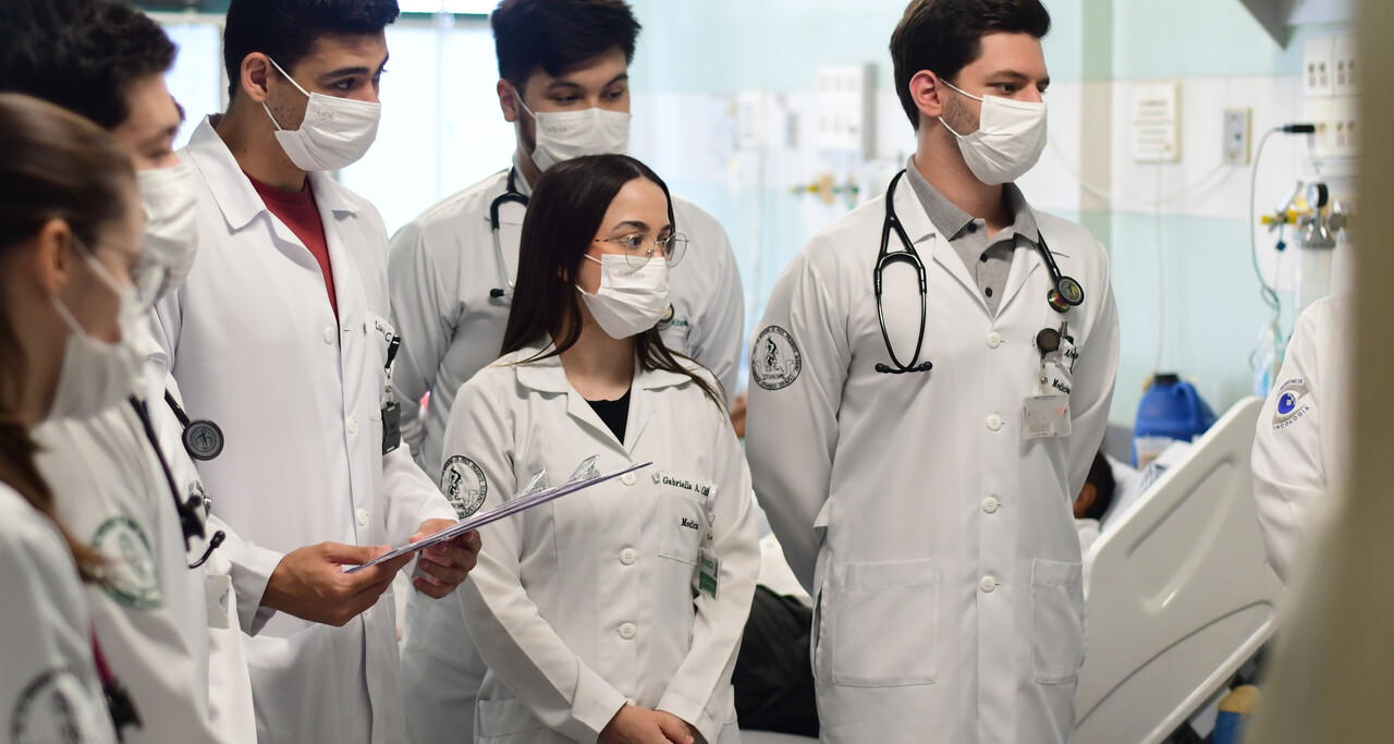 Equipe médica em reunião clínica, com jalecos e estetoscópios