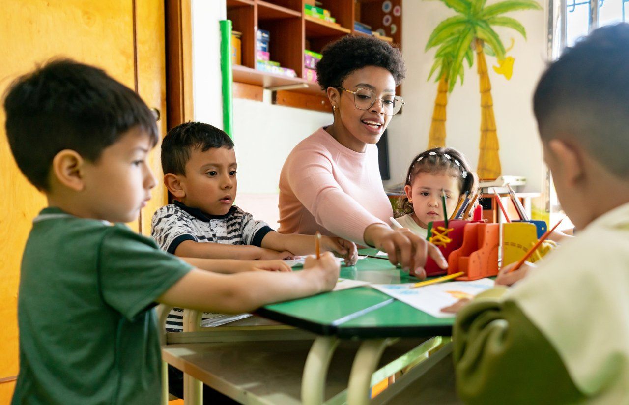 Ambiente de educação infantil, com professora auxiliando crianças em atividade lúdica