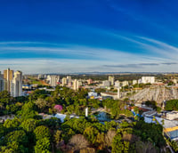 Vista aérea de São José dos Campos, SP, com skyline urbano e áreas verdes ao fundo.