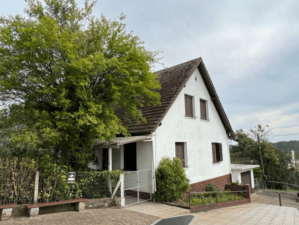 Paisagem urbana em pequena cidade gaúcha, com casas, vegetação e calçamento, ilustrando o cotidiano de um município do interior do RS.