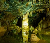 Formações rochosas da Gruta de Botuverá, em ambiente subterrâneo, com reflexos na água