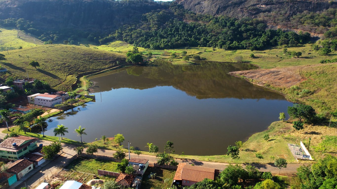 Vista aérea de cidade do interior de Minas Gerais, com morros ao fundo e lago, em fim de tarde