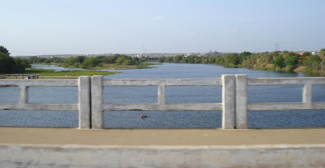 Vista urbana do interior cearense, com curso d’água e vegetação, sugerindo paisagem de cidade do semiárido