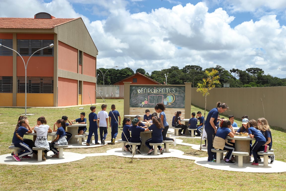 Ambiente de ensino: atividade educativa em espaço aberto, com quadro e mesas coletivas