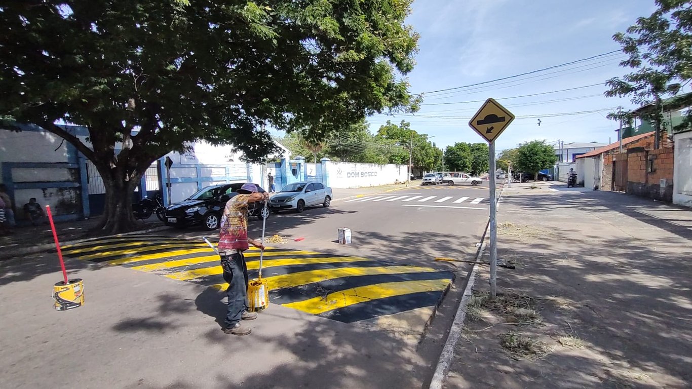 Profissionais de manutenção viária trabalhando em via pública com cones e faixas recém-pintadas