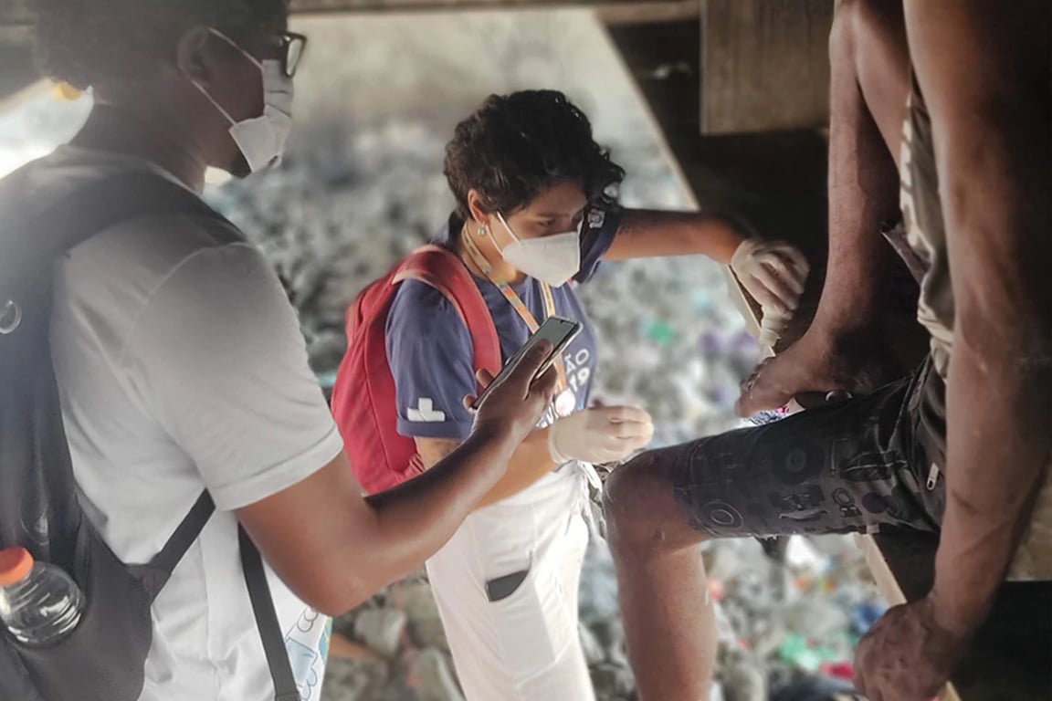 Profissionais de saúde comunitária em atendimento em área urbana, em registro documental horizontal