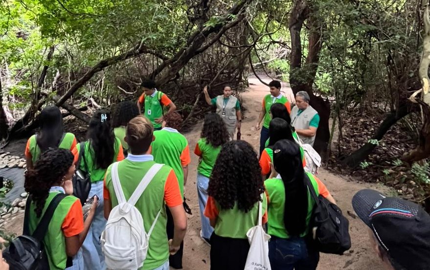 Equipe de campo caminhando por trilha em unidade de conservação, com equipamentos simples