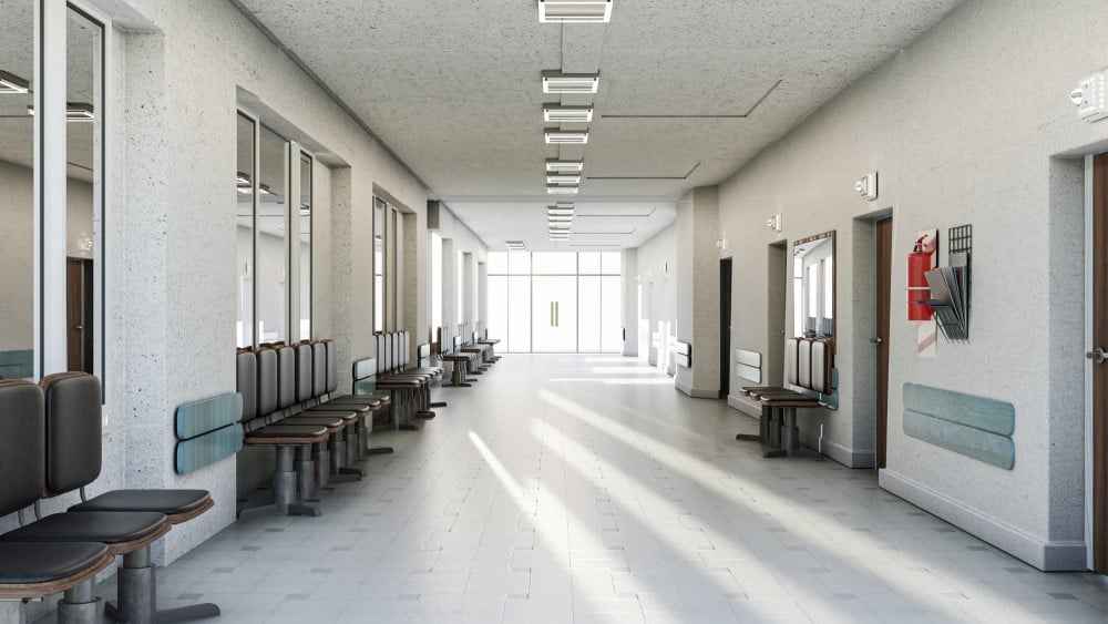 Corredor amplo em hospital público, com sinalização e cadeiras de espera, em luz natural