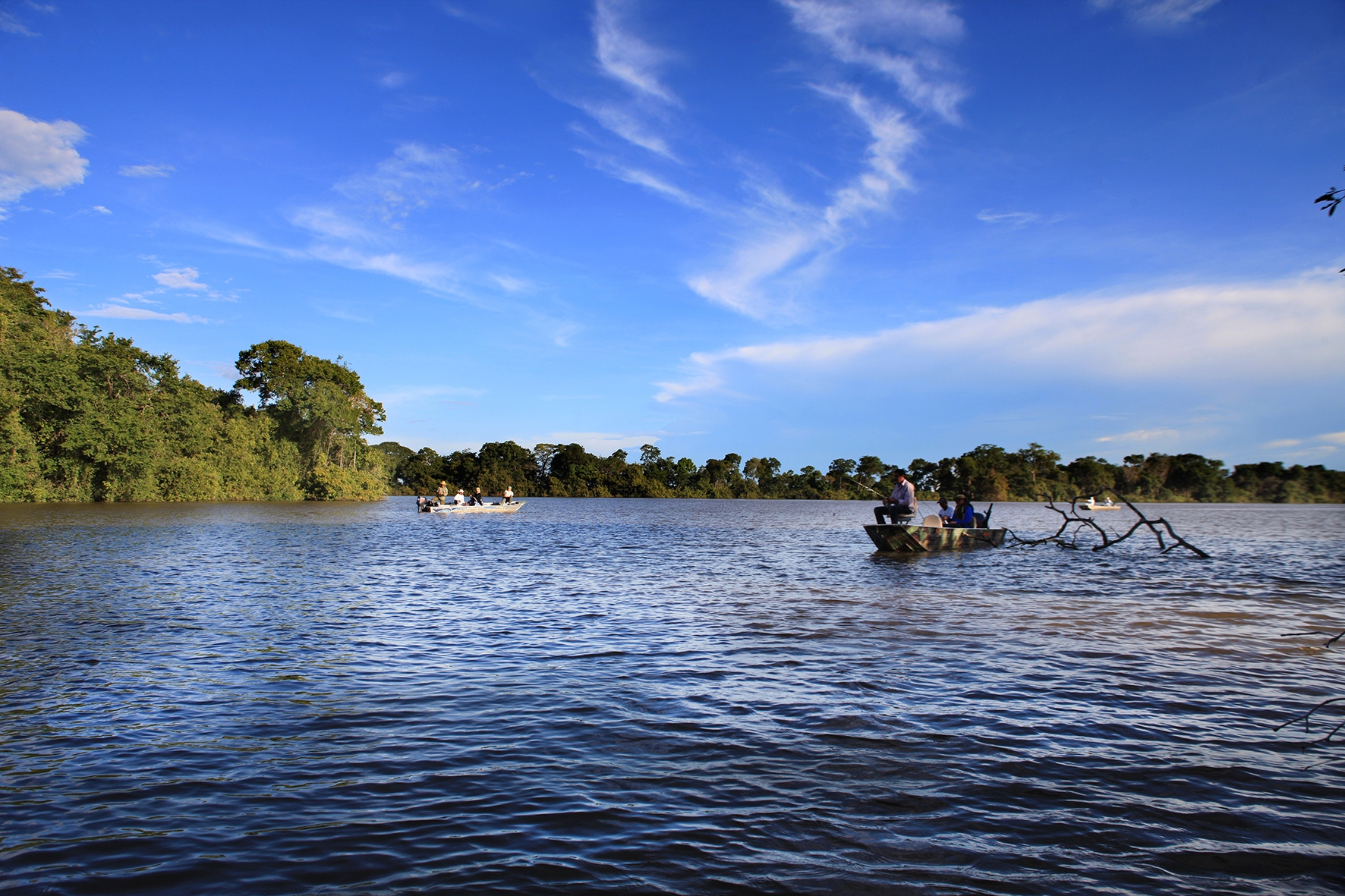 Rio Aporé na divisa GO-MS, com vegetação de cerrado e barcos de pesca ao fundo