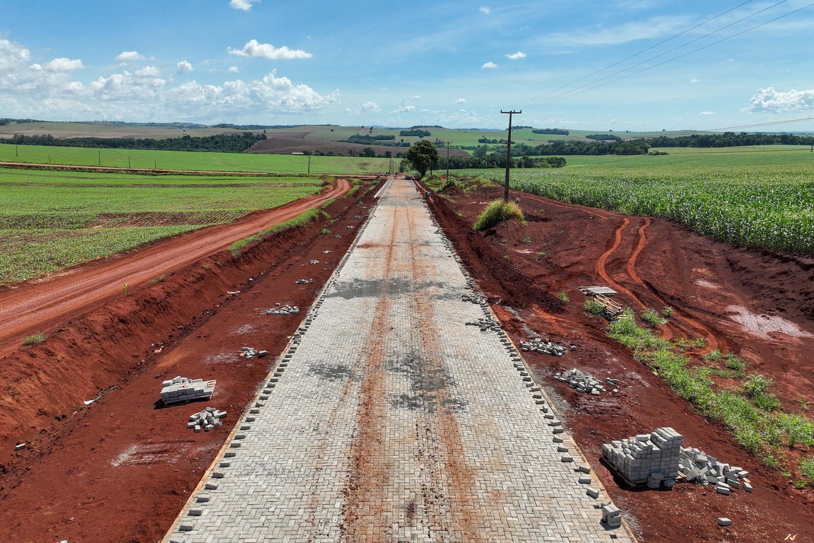 Paisagem rural do Noroeste do Paraná, com estrada vicinal e lavouras ao fundo sob céu azul.