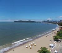 Vista panorâmica da praia de Balneário Piçarras em dia ensolarado, com mar azul e cidade ao fundo