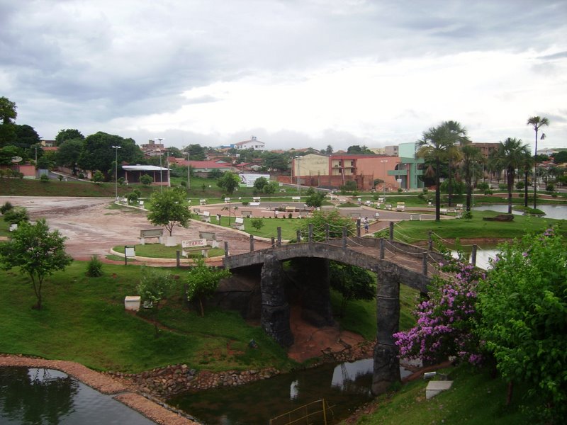 Vista aérea de São Luís de Montes Belos GO, com área urbana, praça e lago ao entardecer