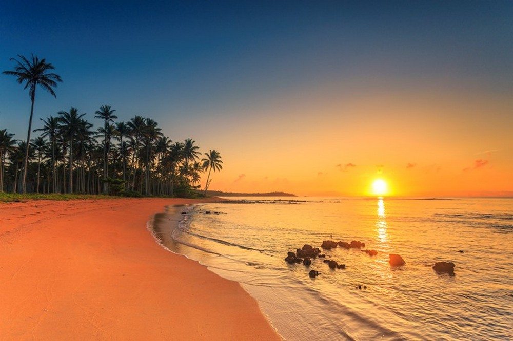 Paisagem costeira de Aracruz ES ao pôr do sol, com praia e coqueiros