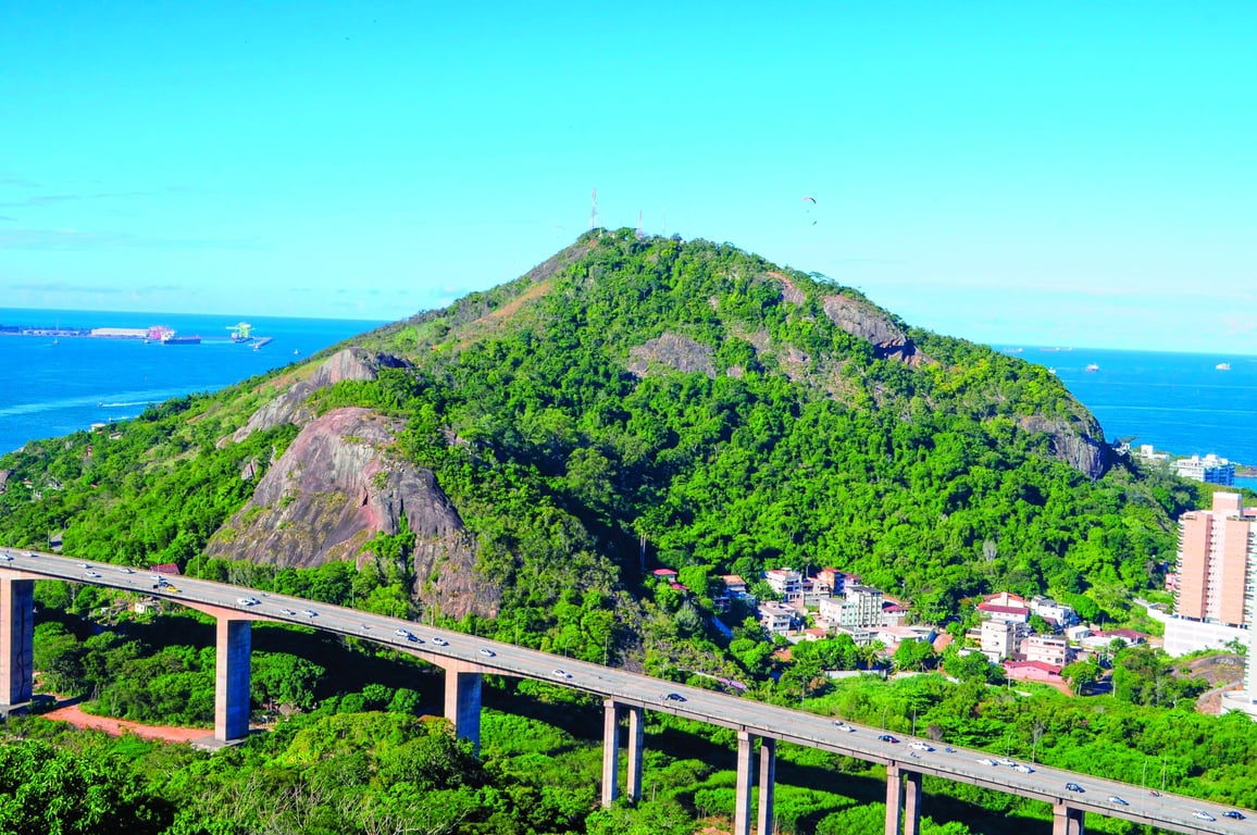 Vista urbana do interior do Espírito Santo, com morros verdes ao fundo e céu claro