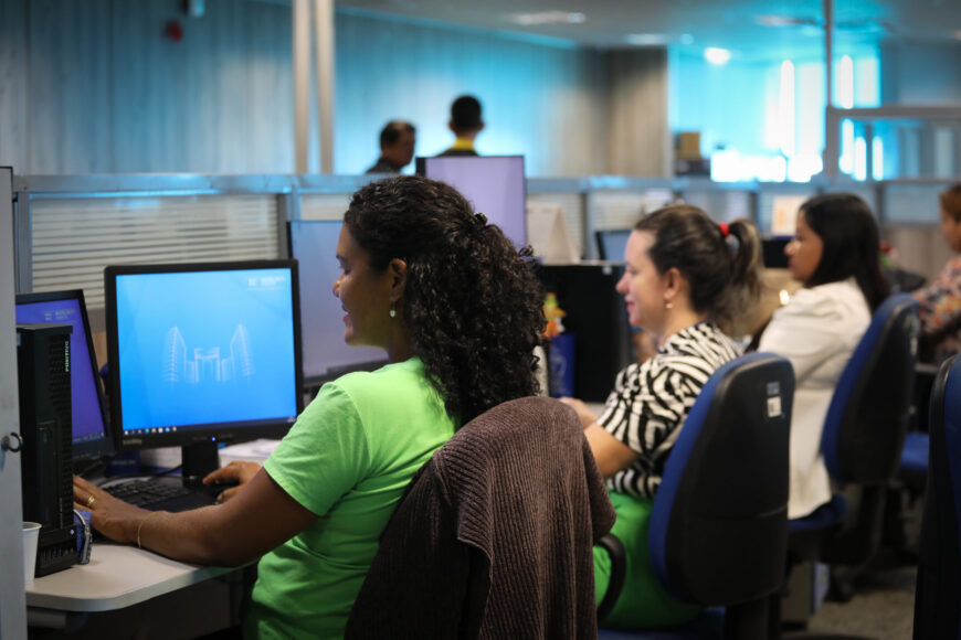 Equipe trabalhando em escritório público, representando áreas administrativa e de TI