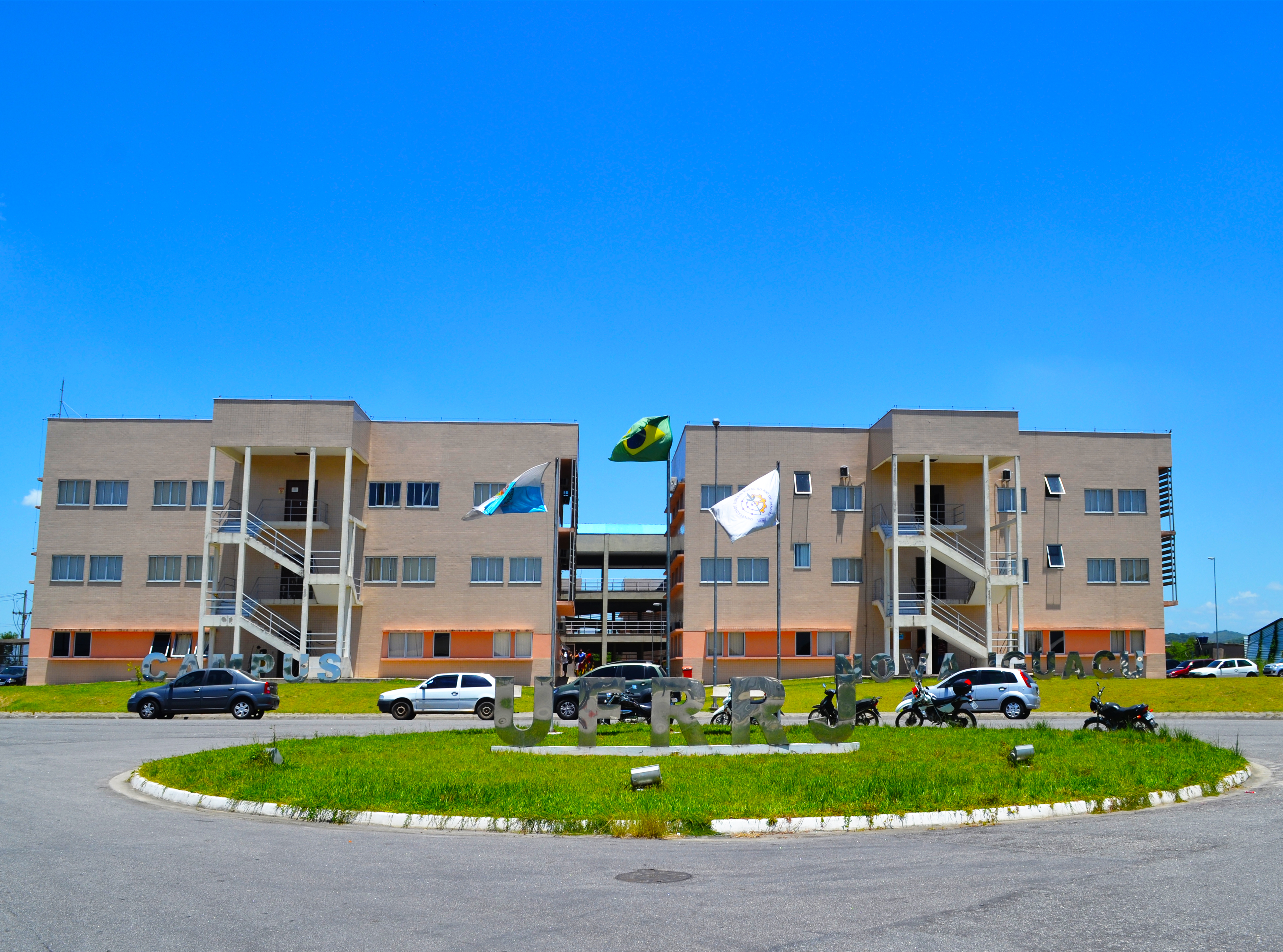 Entrada do campus da UFRRJ em Seropédica, com bandeiras e área verde ao fundo