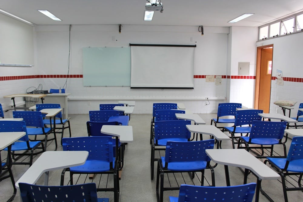 Ambiente acadêmico moderno com quadro branco e cadeiras azuis, sem alunos, em perspectiva horizontal