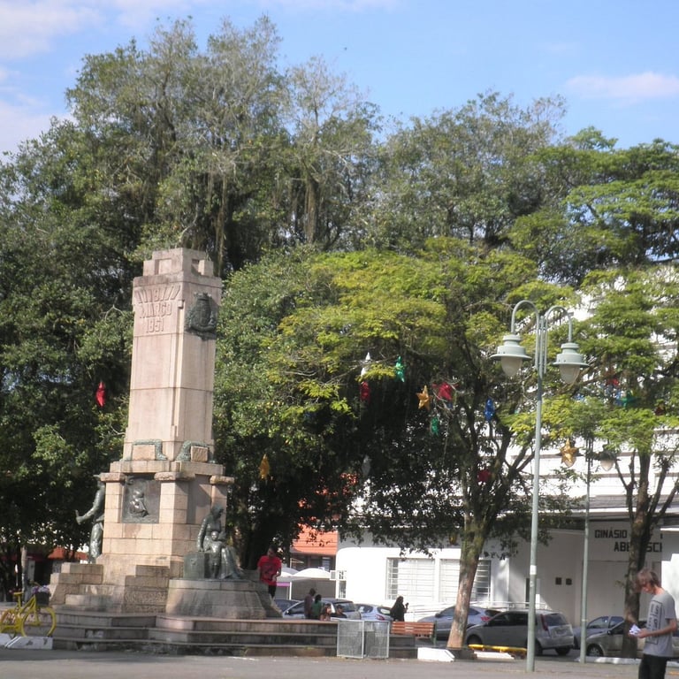 Praça central de cidade do interior gaúcho com monumento e áreas verdes