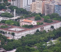 Foto aérea do campus da UNIRIO na Urca, mostrando prédios universitários e áreas verdes.