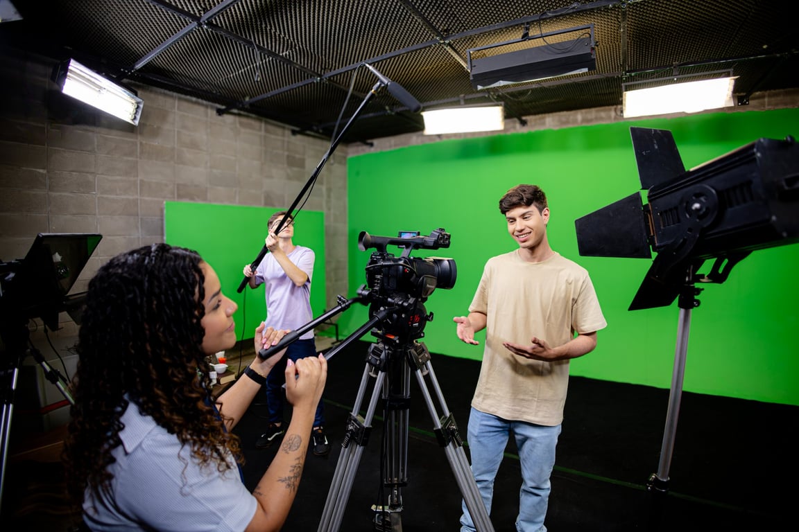 Ambiente universitário com alunos operando câmeras e luzes em estúdio de audiovisual