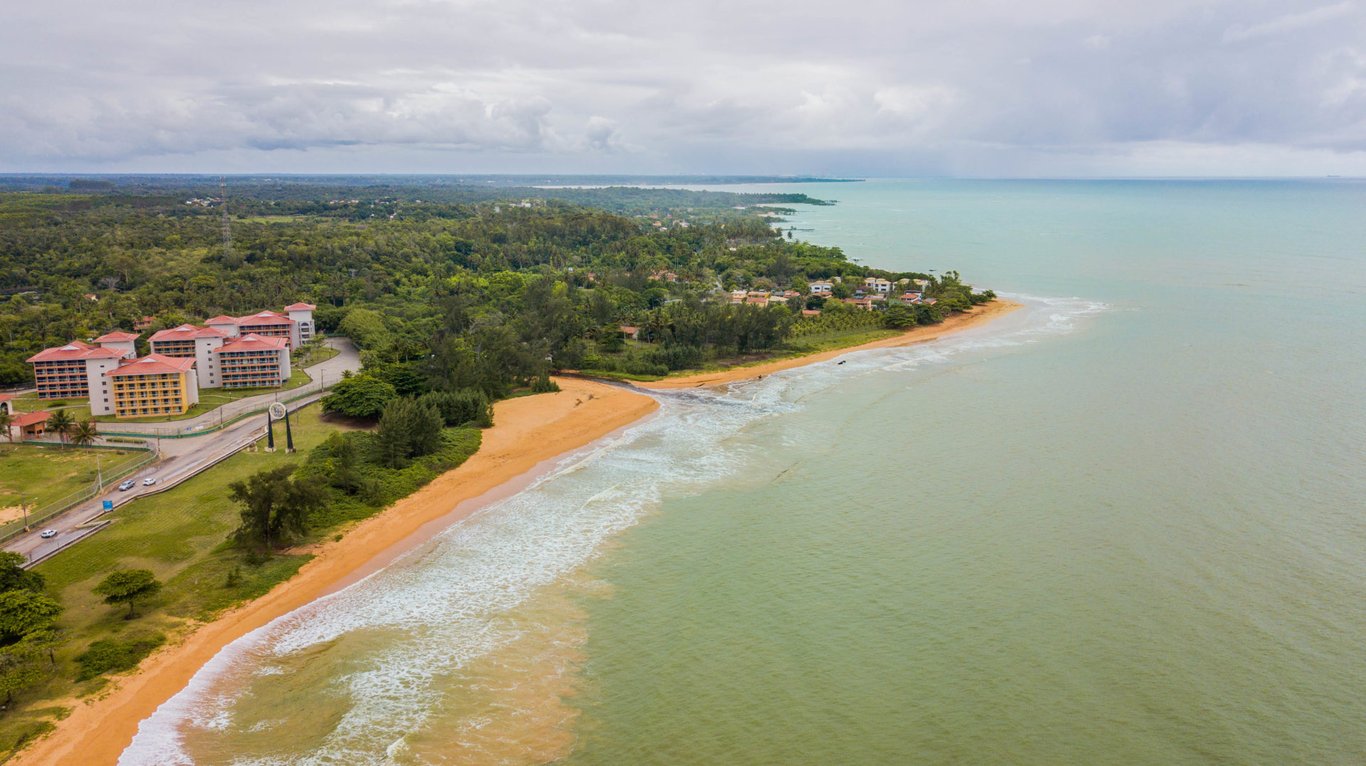 Vista aérea de Aracruz ES, com faixa de areia, mar e área urbana ao fundo