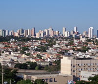 Vista urbana de cidade do interior paulista em dia ensolarado, com prédios baixos e área residencial ao fundo