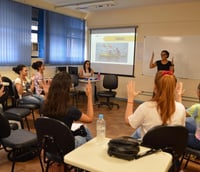 Intérprete de Libras em ambiente acadêmico, com estudantes ao fundo.