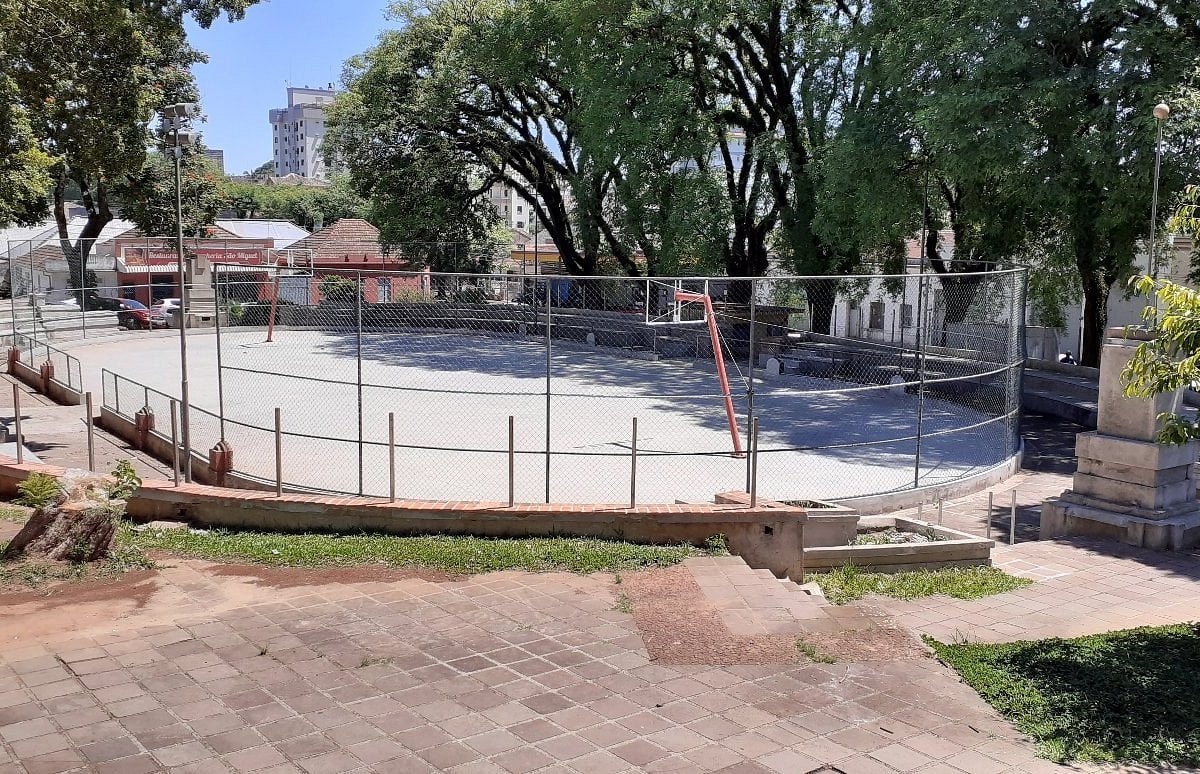 Praça central de cidade do interior com quadra e arborização