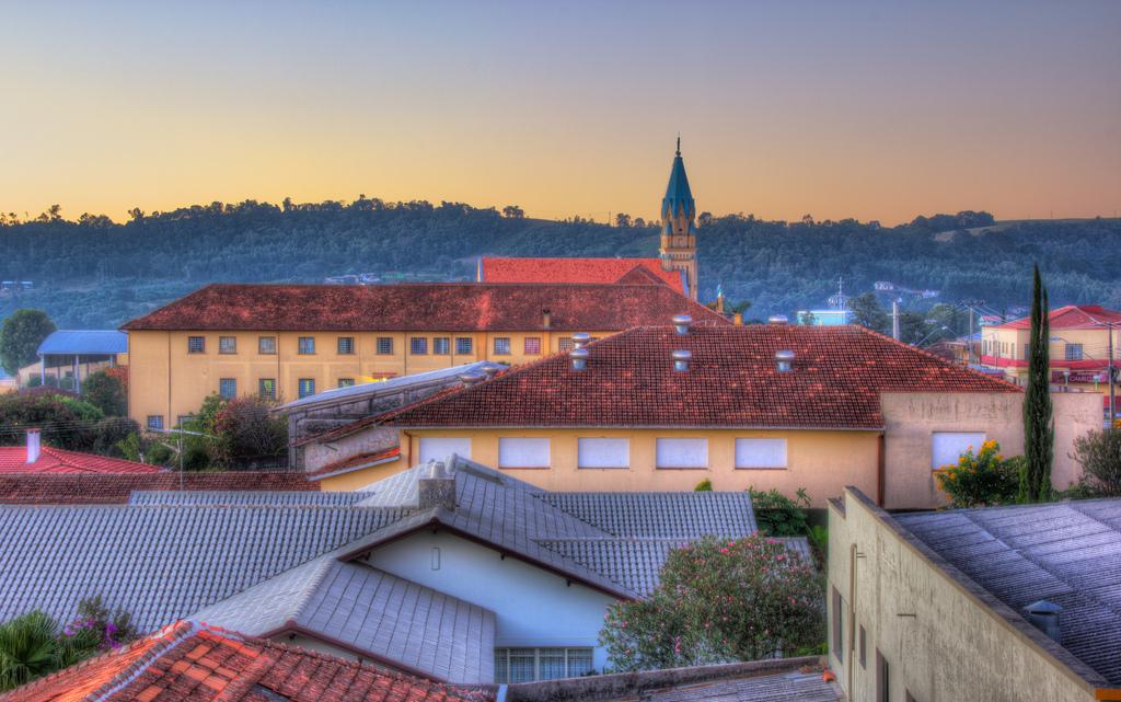 Paisagem urbana de uma cidade do interior do Paraná, com prédios baixos e uma igreja ao fundo.