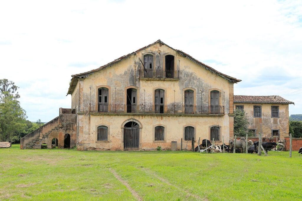 Cenário rural no Centro-Oeste, com arquitetura simples e paisagem de pastagem