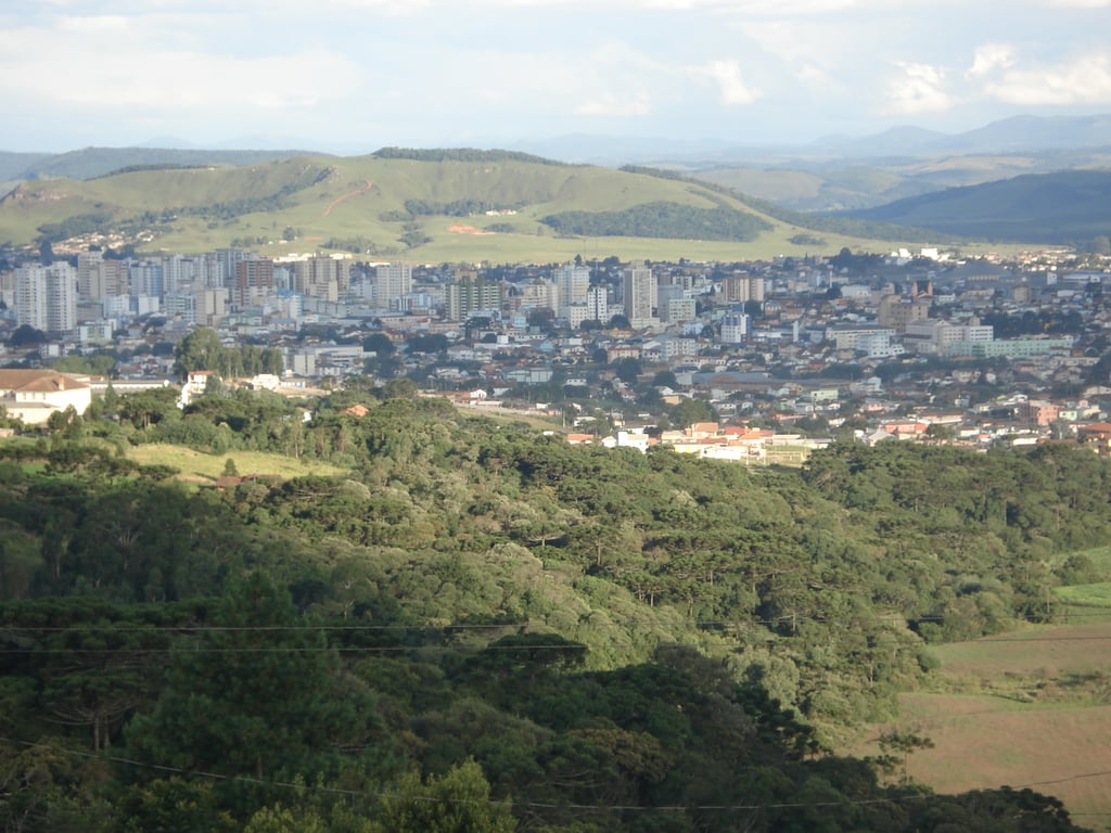Vista aérea de Lages SC, na Serra Catarinense, com área urbana e campos ao redor, sob céu aberto.