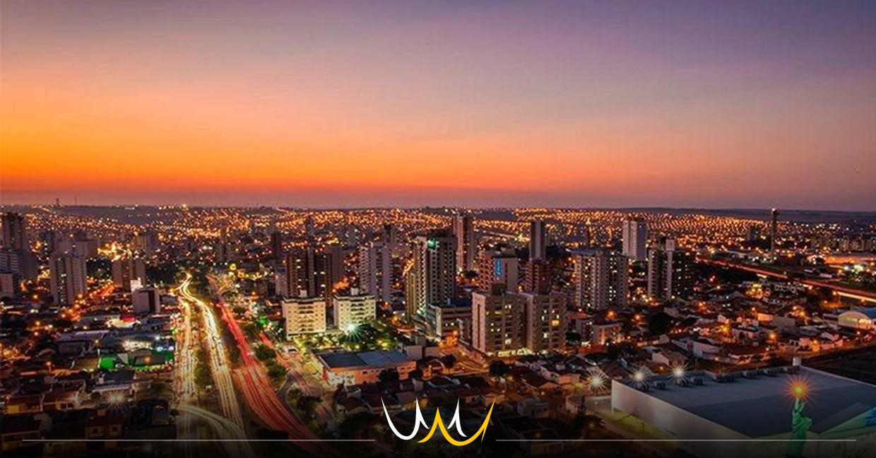 Vista aérea de Bauru ao entardecer, com prédios, áreas verdes e avenidas em tons quentes
