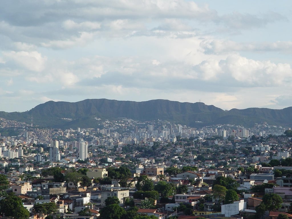 Vista panorâmica de Belo Horizonte ao entardecer, com prédios e a Serra do Curral ao fundo