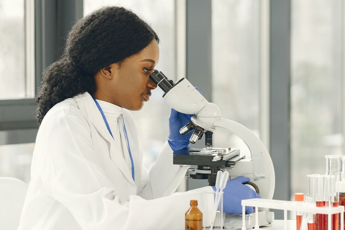 Profissional em laboratório de análises clínicas, operando microscópio e equipamentos de bancada