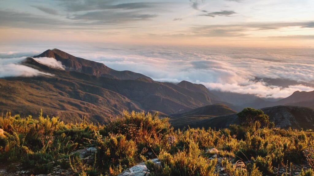 Amanhecer no Parque Nacional do Caparaó, com cadeias de montanhas e vegetação de campos de altitude ao fundo