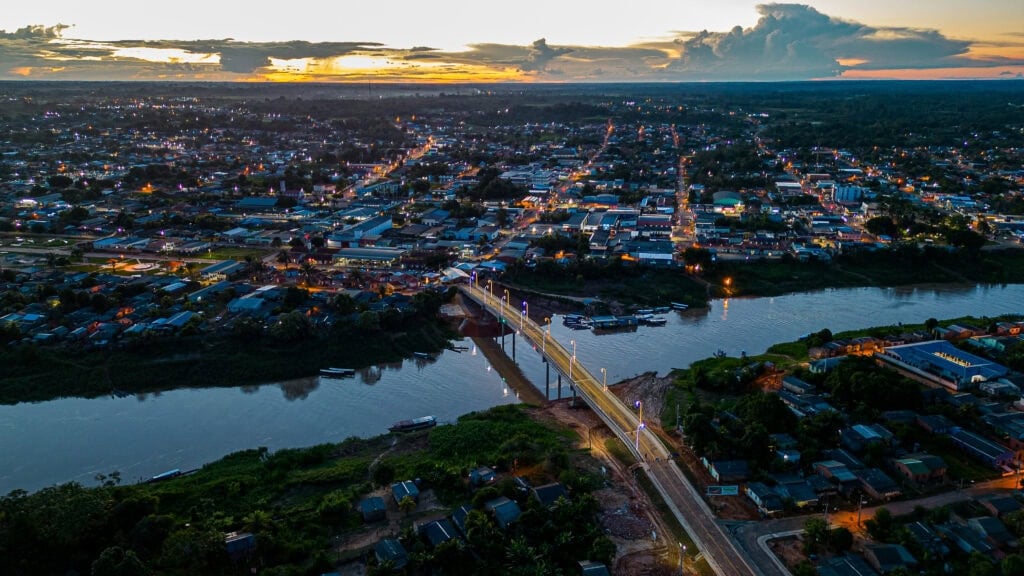 Vista aérea de Rio Branco, com ponte iluminada sobre o rio Acre ao entardecer