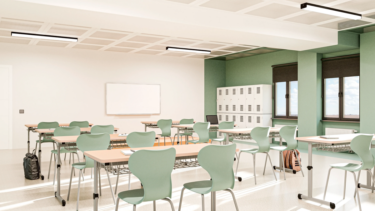 Sala de provas vazia, com carteiras enfileiradas e luz natural, em composição horizontal