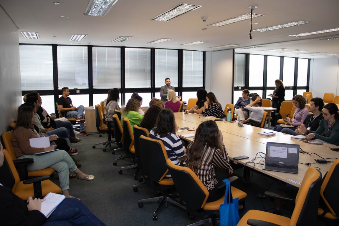 Profissionais de saúde em reunião de planejamento, com laptops e anotações, em ambiente de vigilância em saúde