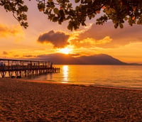 Vista de Florianópolis ao pôr do sol, com mar e píer em primeiro plano